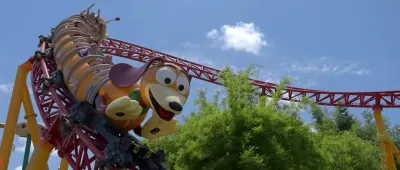 Cartoon dog character on red roller coaster track against blue sky