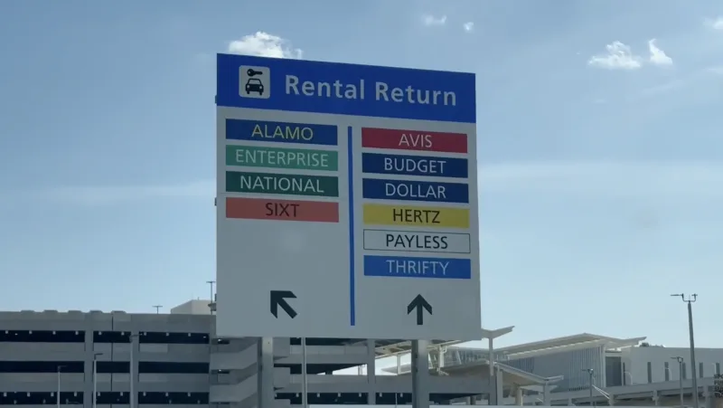 Rental car return directional sign listing multiple companies at airport parking garage