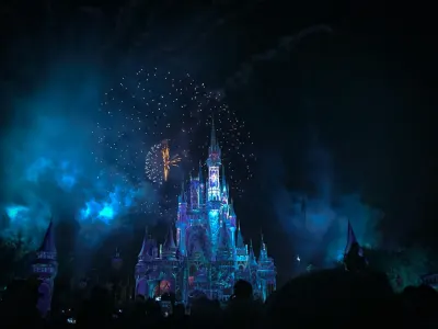Cinderella Castle illuminated at night with fireworks display overhead