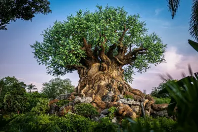 Giant tree sculpture with carved animals at base in tropical setting