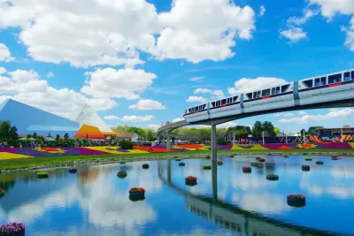 Monorail over colorful flower gardens and pond at theme park