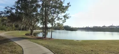 Waterfront residential area with cypress trees, walking path, and calm lake