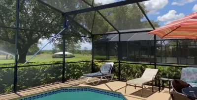 Screened pool area with lounge chairs overlooking Florida landscape