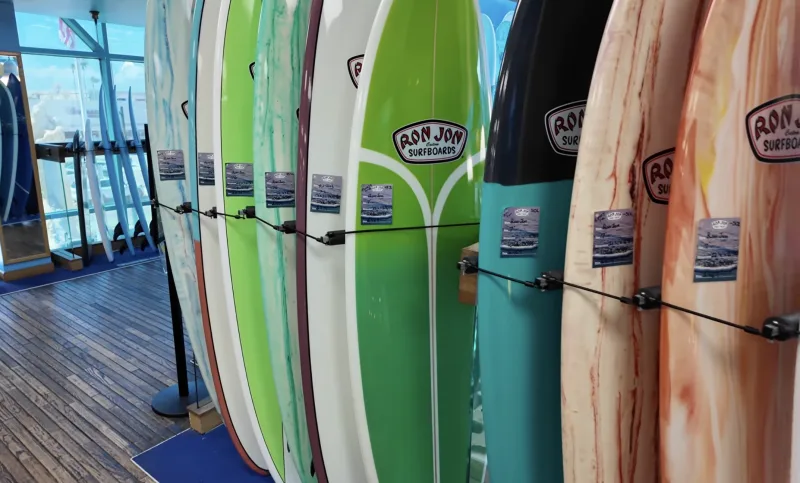Row of colorful Ron Jon surfboards displayed on rack in shop